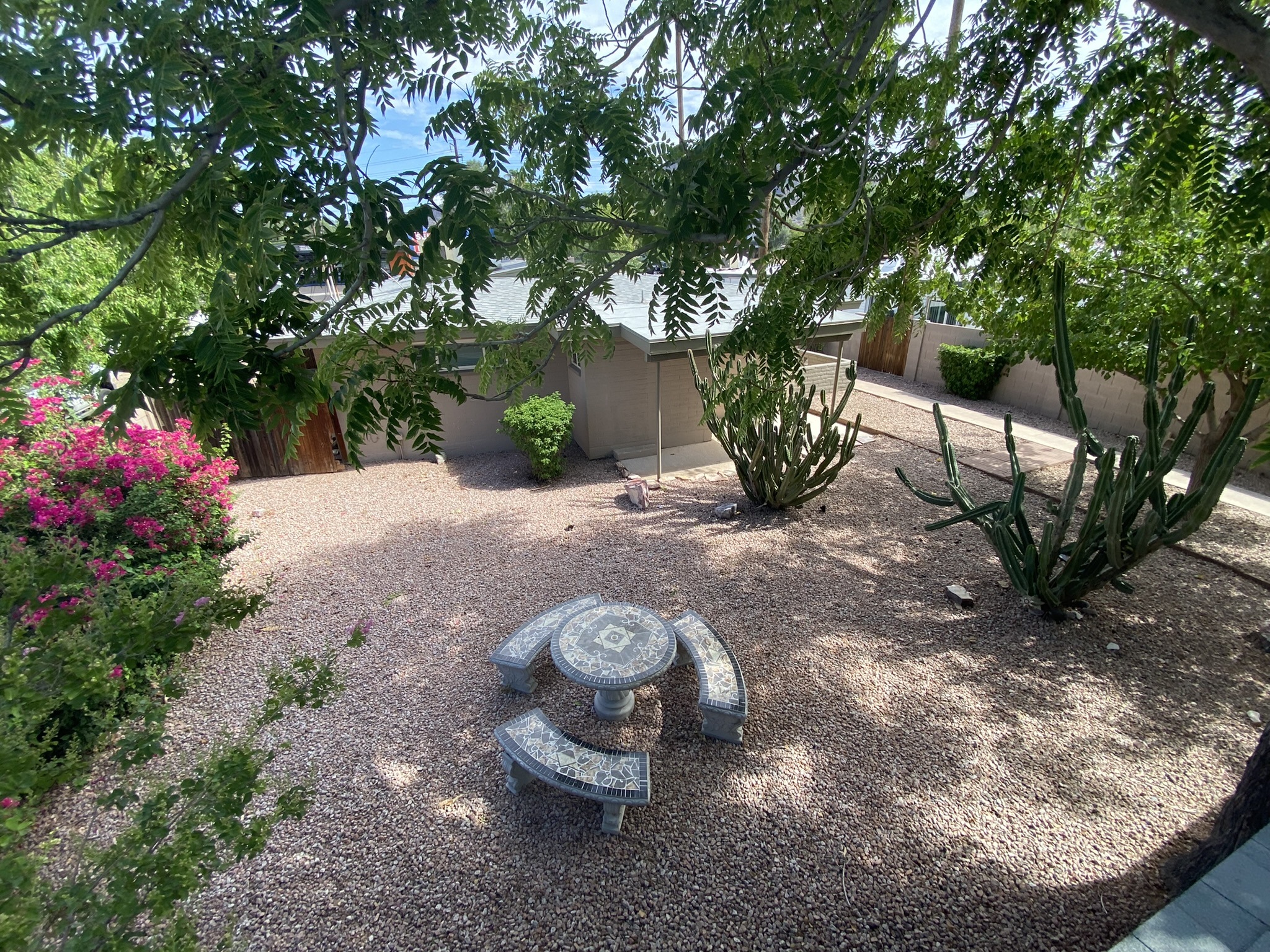 A garden with a stone table and chairs surrounded by greenery.
